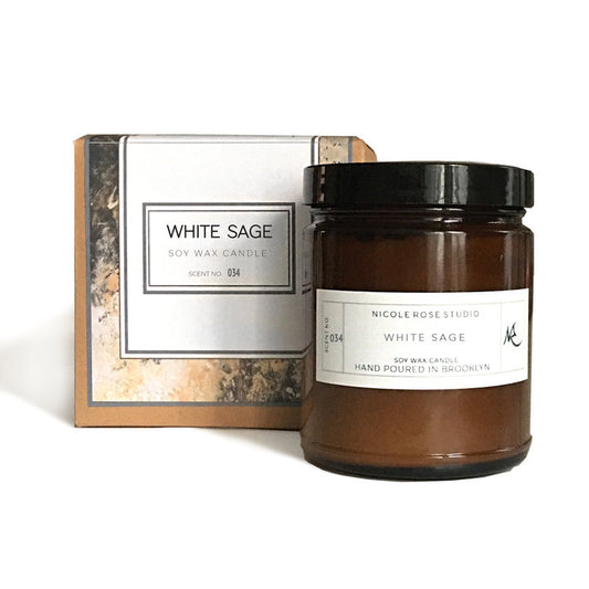 A white soy wax candle in a glass jar, labeled "White Sage Aromatherapy".